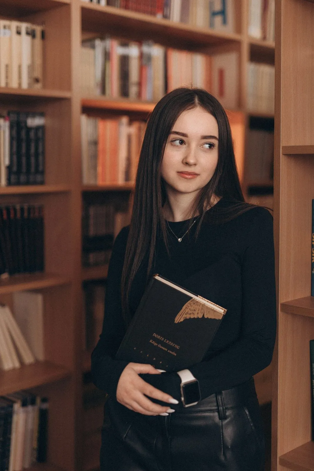 Выпускница с книгой у книжных полок
